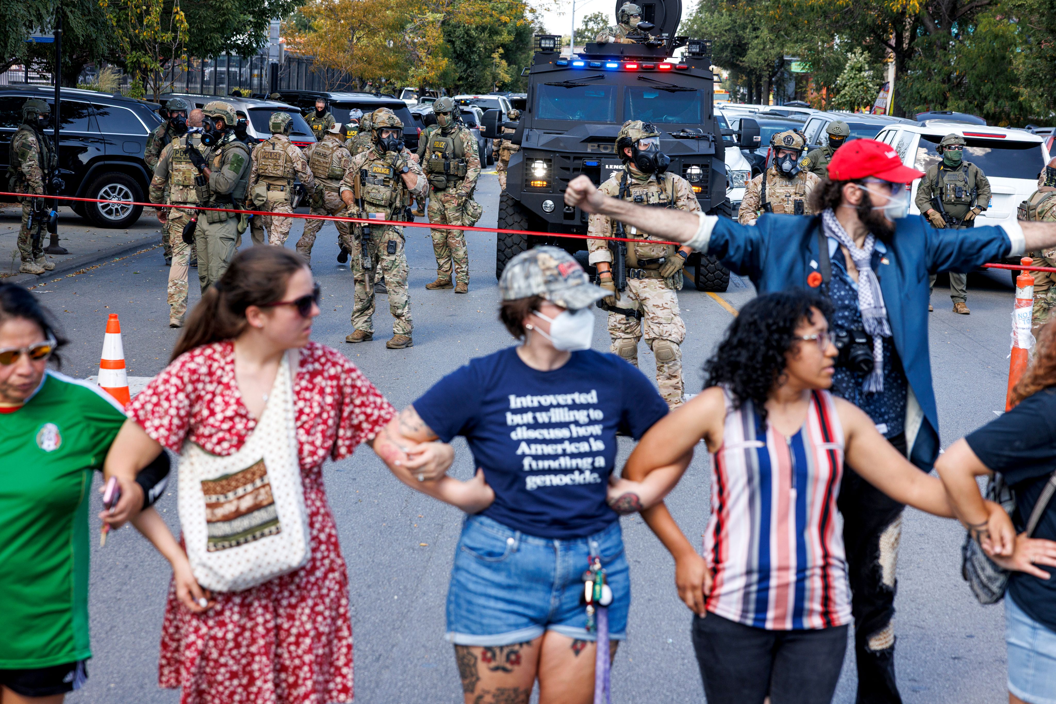 Protesters create a line to maintain distance from ICE officers in the Brighton Park neighborhood, Oct. 4, 2025, after learning that U.S. Border Patrol shot a woman. (Anthony Vazquez/Chicago Sun-Times via AP)
